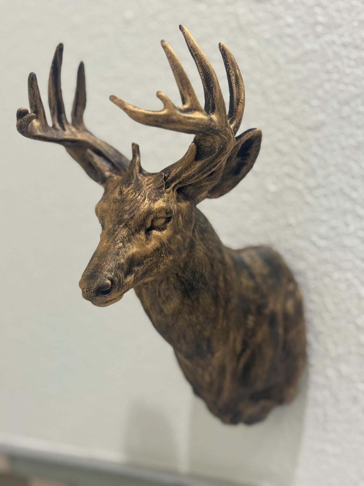 Angled view of antique gold faux deer head wall mount with detailed antlers