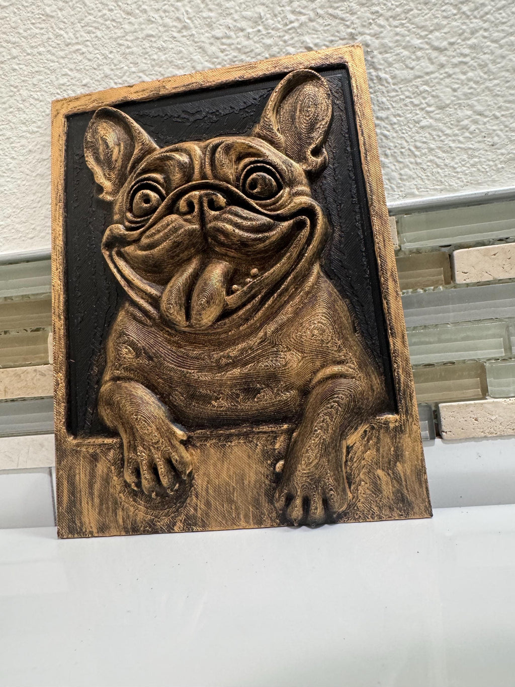 Slight angle of the gold and black bulldog plaque with paws on the ledge