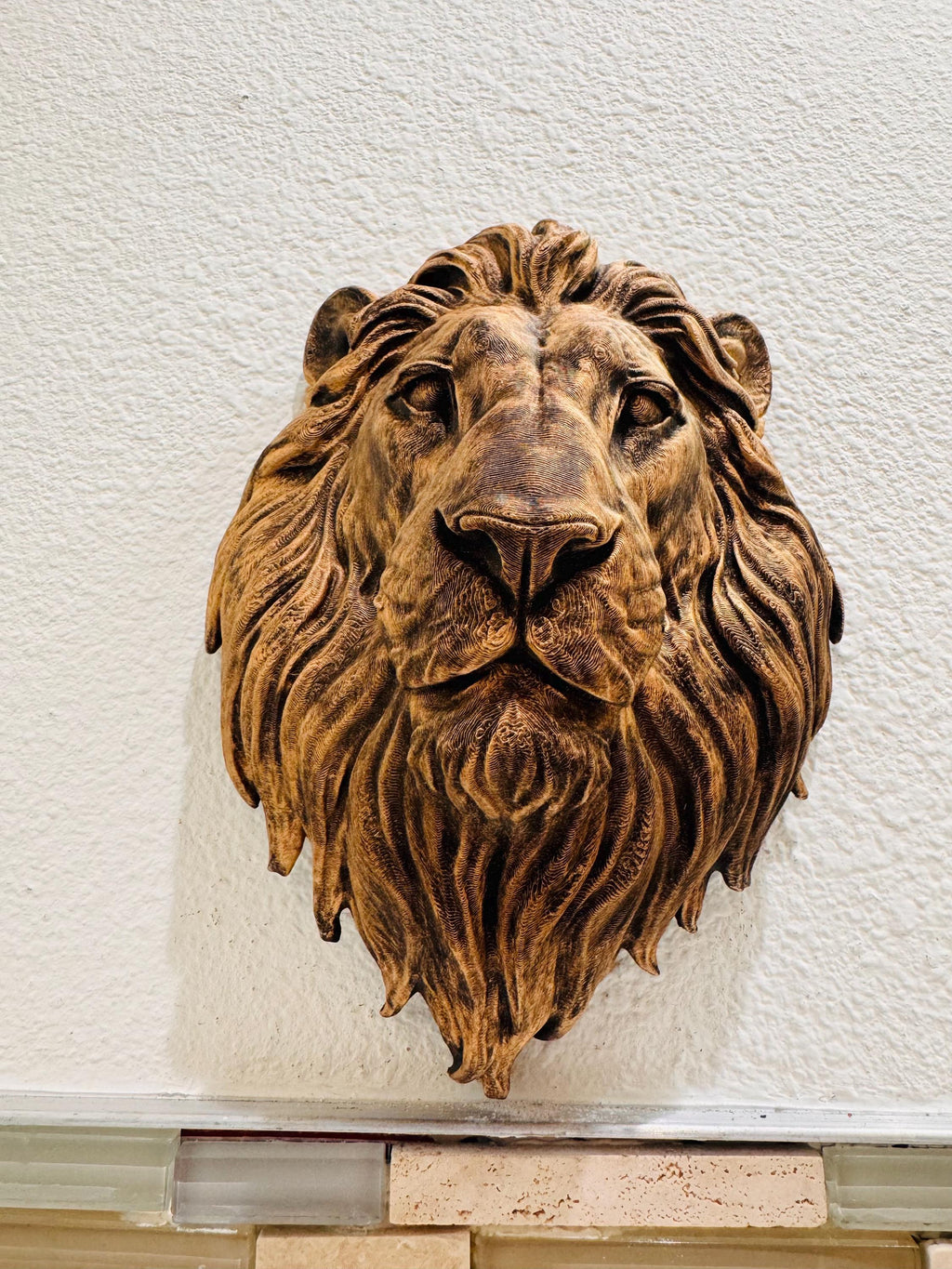 Front view of the bronze lion head on a textured wall