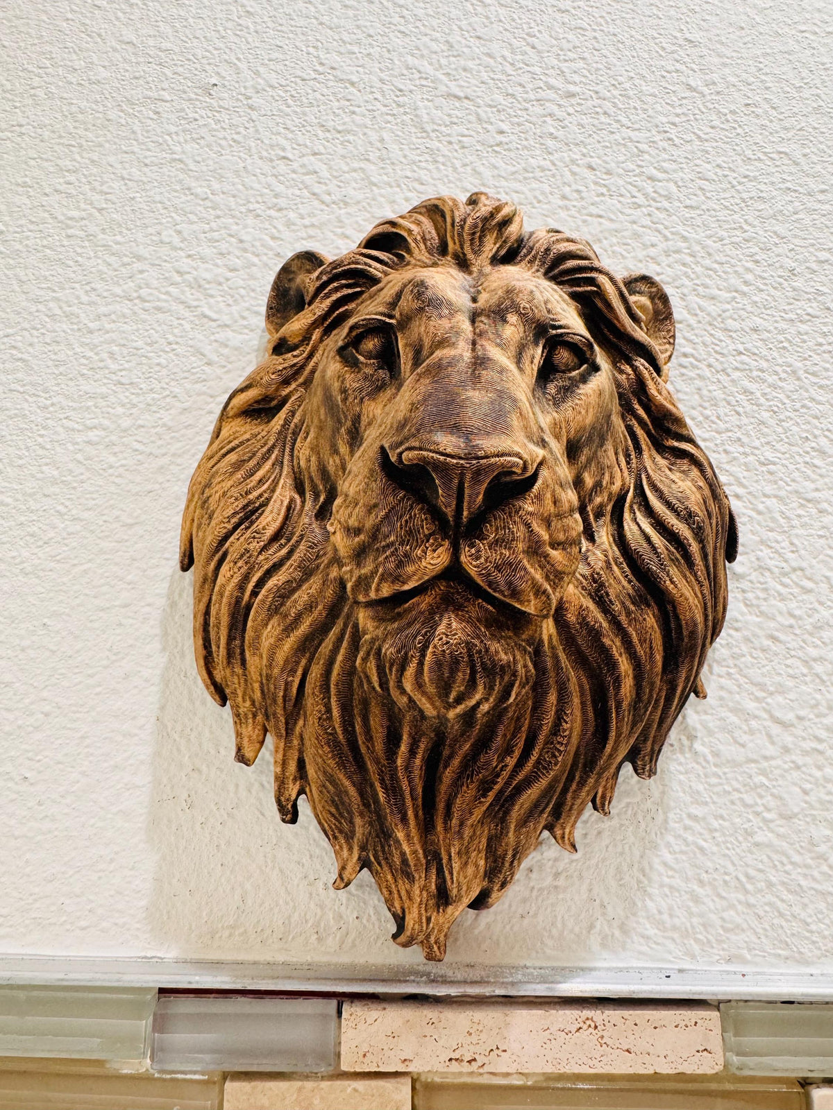 Front view of the bronze lion head on a textured wall