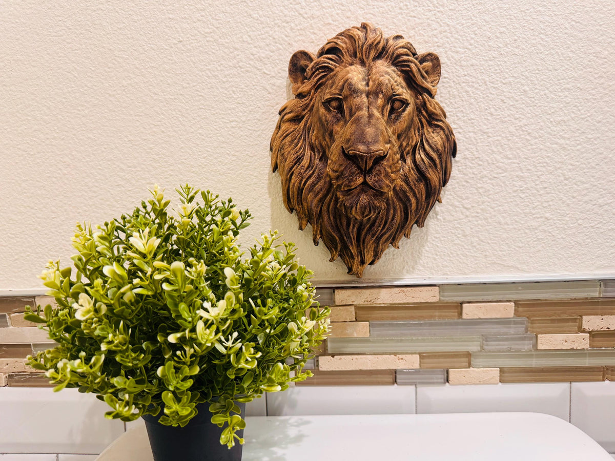 Bronze lion head hung above a potted plant on a counter