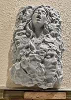 Front view of the stone relief with faces and rocky texture