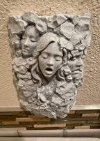 Low front view of the stone faces relief showing the central face with closed eyes