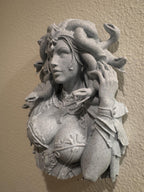 Angled side view of stone-look Medusa bust mounted on a textured wall