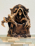 Close front view of the screaming reaper skull and hands over the tombstone