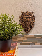 Horned demon sculpture hung above a plant and books on a kitchen counter