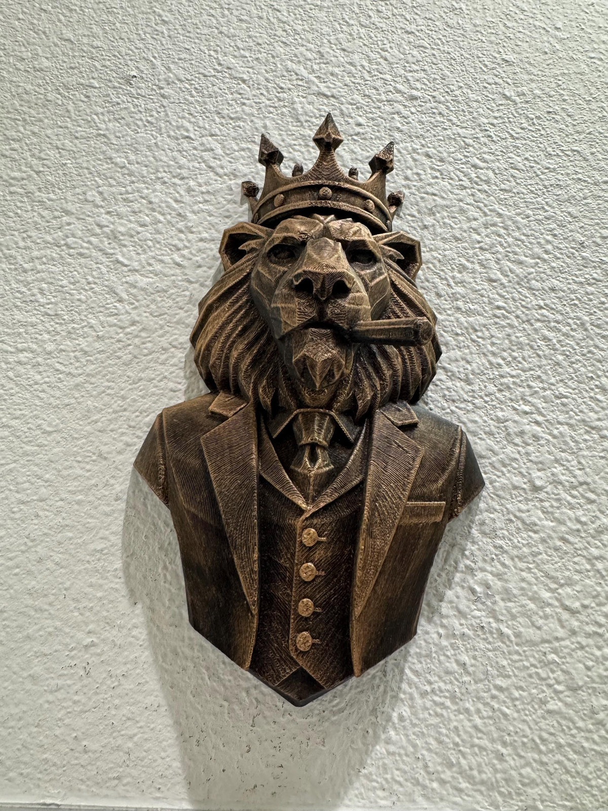 Front view of the crowned lion boss bust on a textured wall