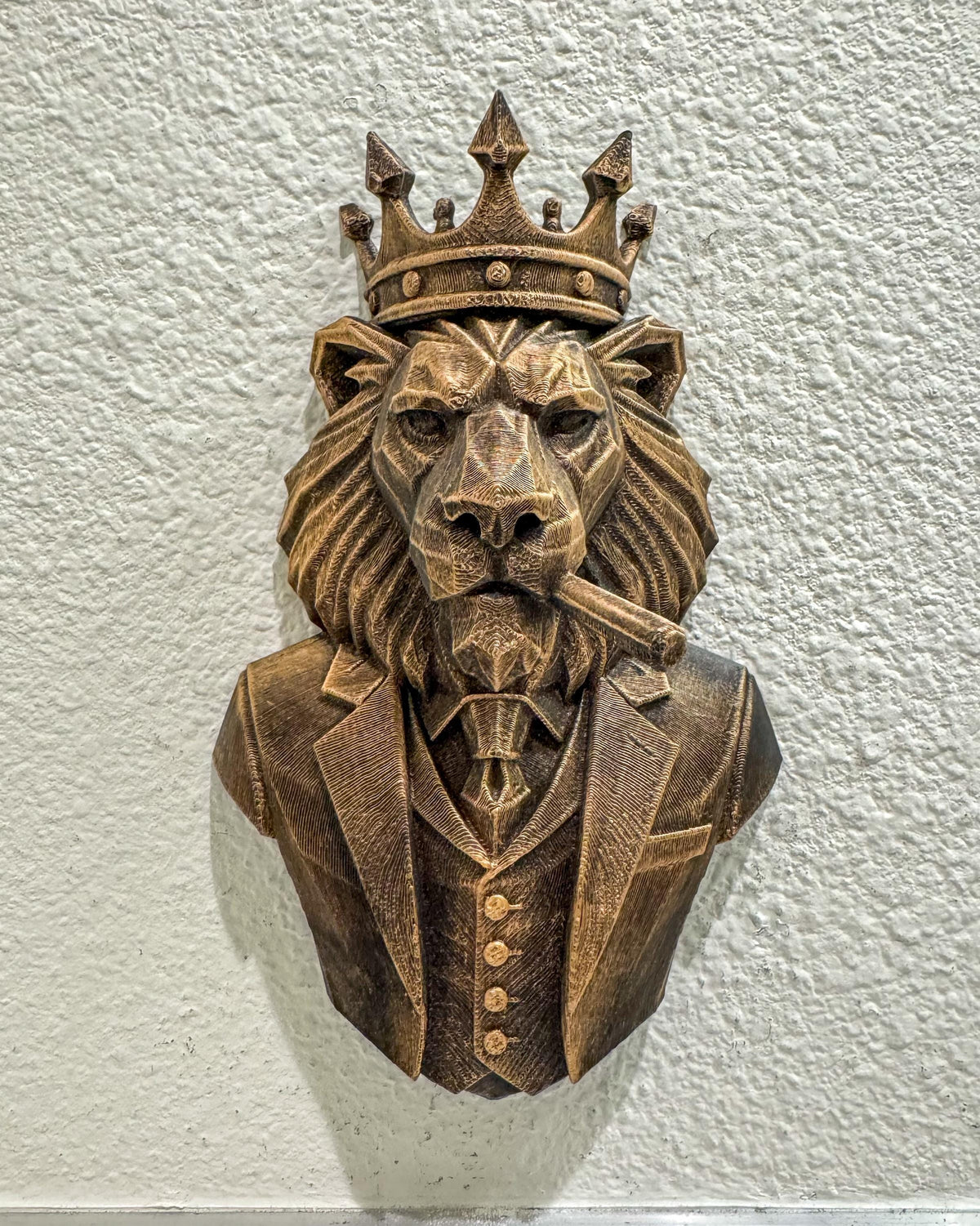 Front view of antique bronze geometric lion boss bust with crown, suit and cigar