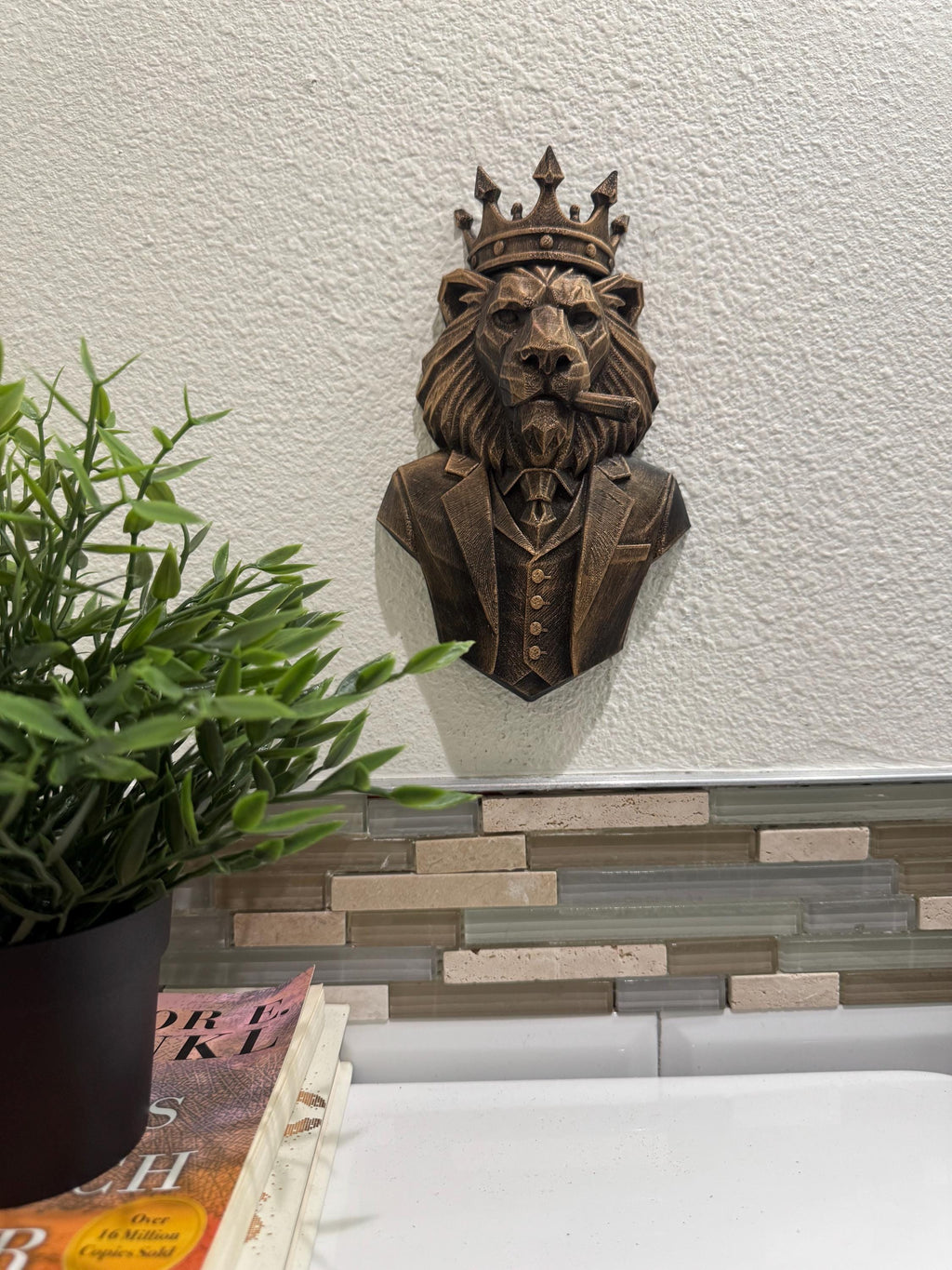 Lion boss sculpture hung above a plant and books on a counter