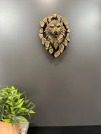 Wolf breaking-through sculpture hung on a gray wall above a potted plant