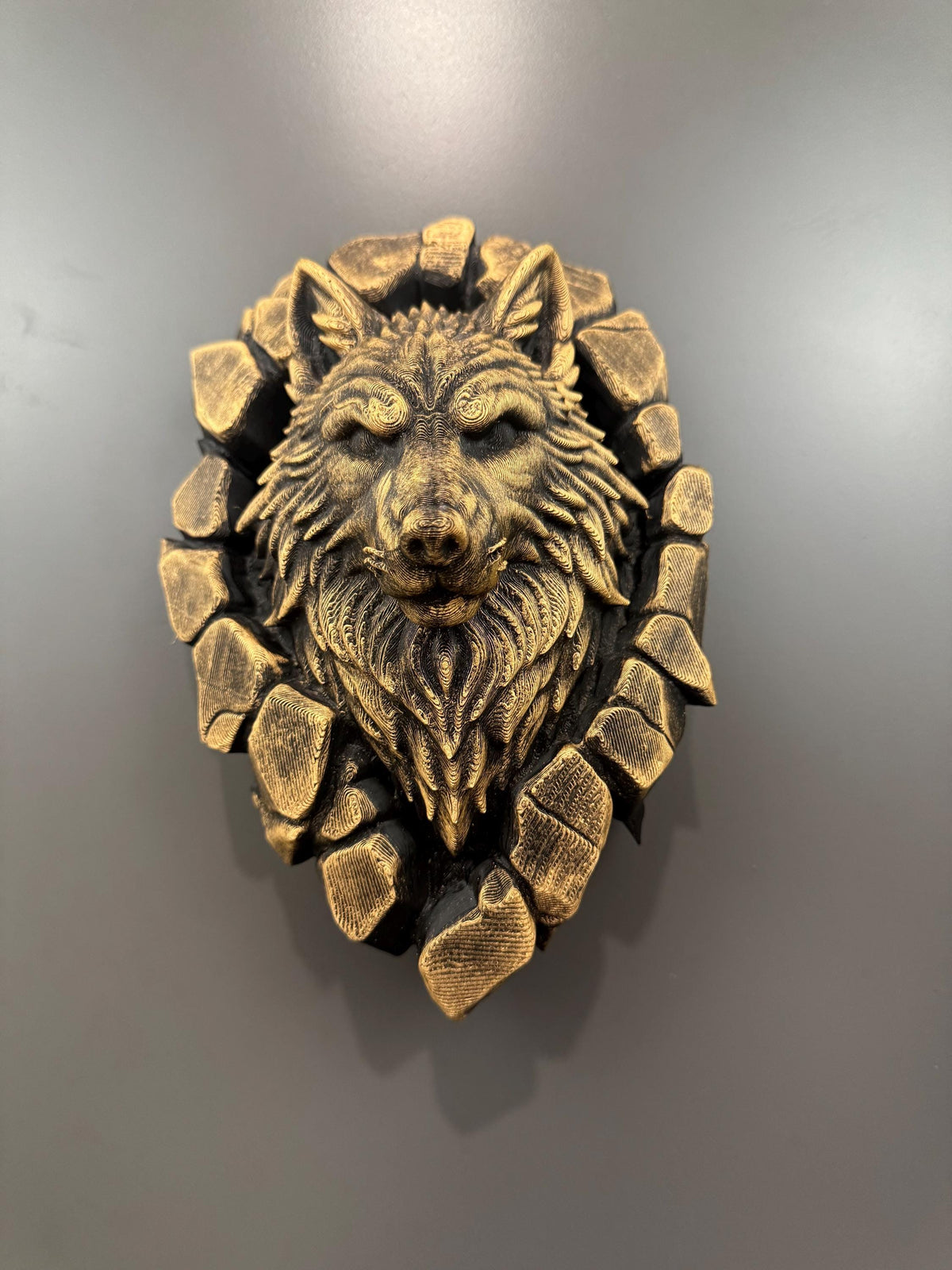 Front view of gold and black wolf head breaking through a ring of stone blocks