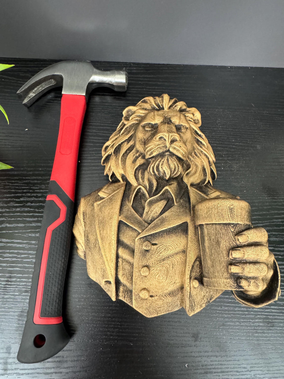 Lion gentleman bust lying beside a hammer for scale