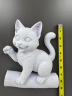 Kitten on log wall sculpture beside a tape measure showing its height