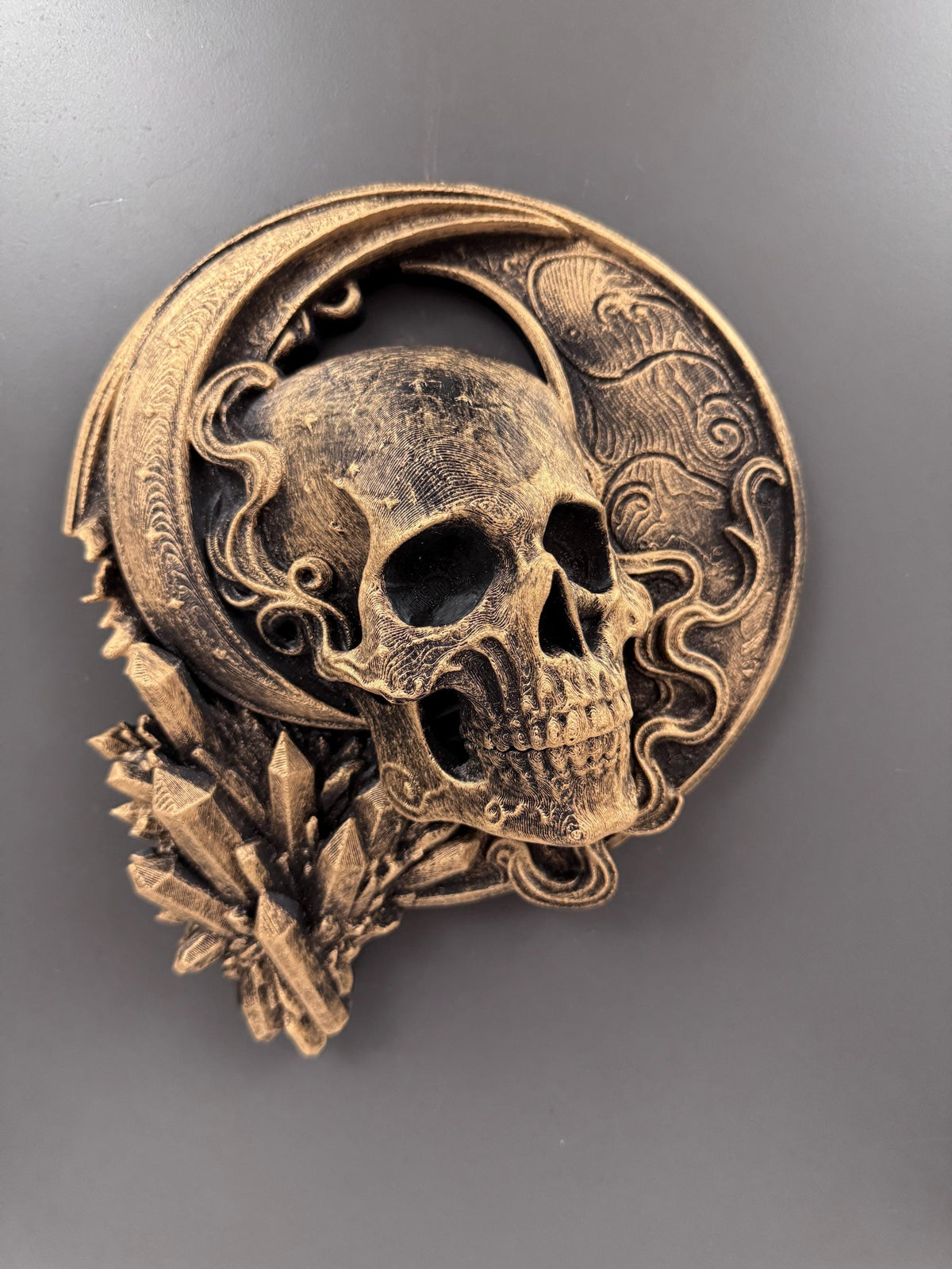 Front view of the antique gold celestial skull on a gray wall