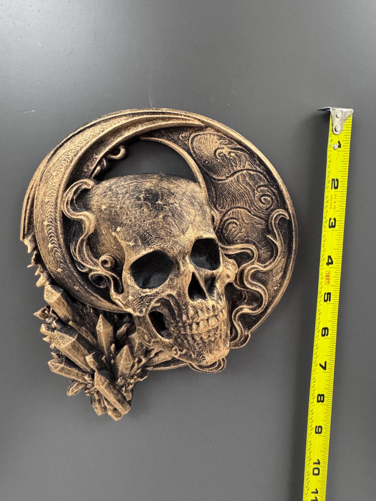 Crescent moon skull sculpture beside a tape measure showing its height