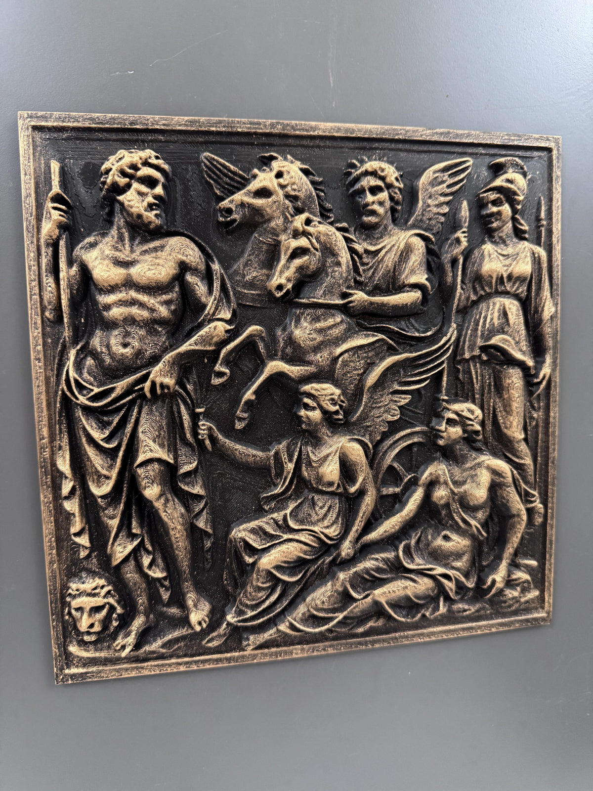 Front view of the Greek gods relief panel on a gray wall