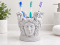 Speckled white Medusa toothbrush holder on a bathroom counter with three toothbrushes