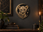 Celestial lioness sculpture on a dark wall above a candle and books