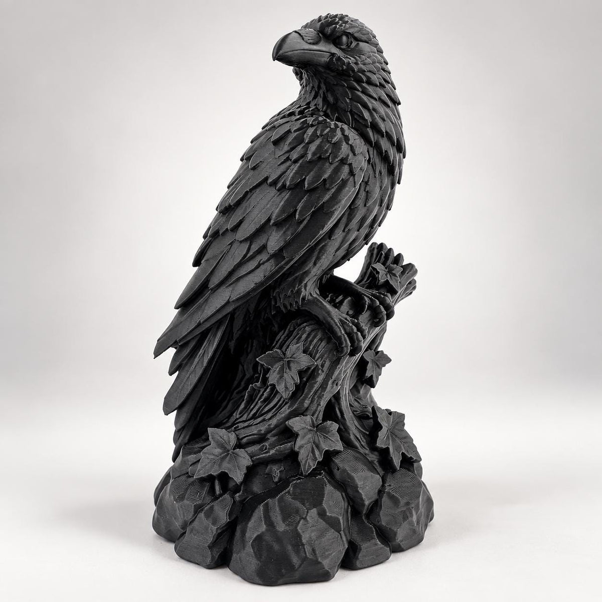 Angled view of black raven statue perched on a twisted trunk with ivy and stones