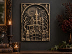 Haunted house sculpture on a dark wall beside a candle and books