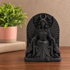 Black Lilith statue on a wooden shelf beside a potted plant and book