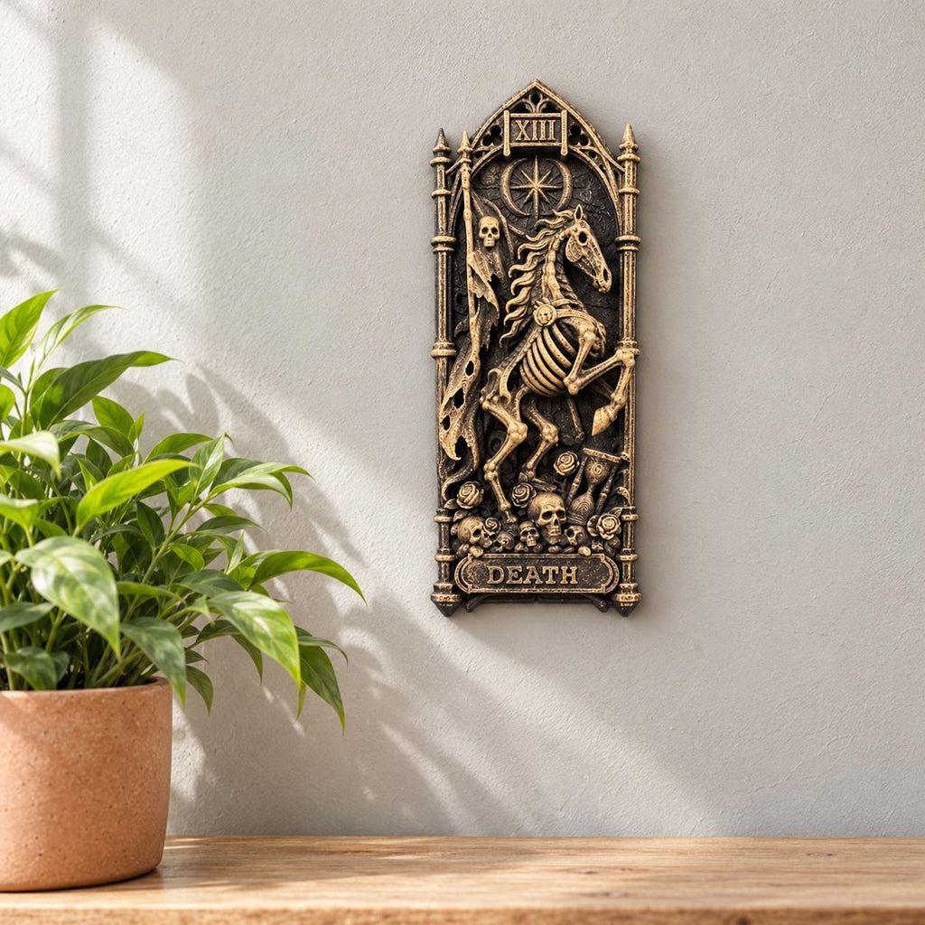 Death tarot wall relief hung beside a potted plant on a wooden shelf