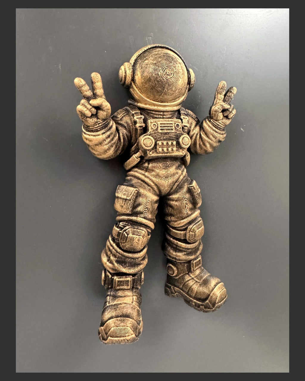 Low angle of the antique gold peace sign astronaut on a gray wall