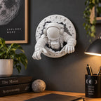 Astronaut moon sculpture hung above a desk with astronomy books and a lamp