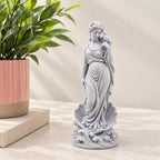 Aphrodite goddess statue standing above a sculpted wave base