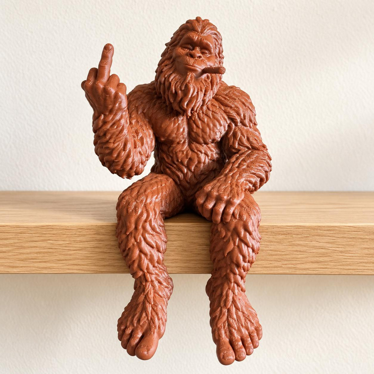 Reddish-brown Bigfoot shelf sitter figurine with a raised middle finger